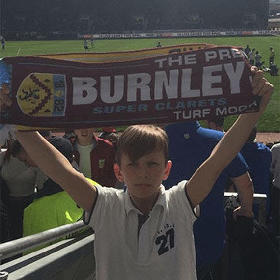 En gutt som holder et Burnley supporterskjerf over hodet